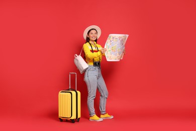 Photo of Happy traveller with map and suitcase on red background