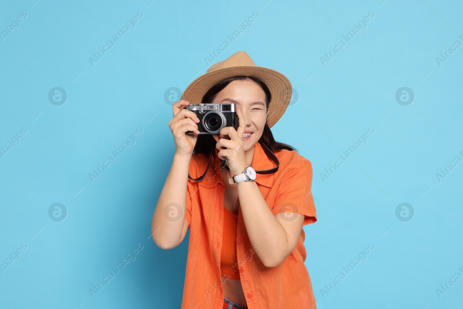 Photo of Happy traveller taking photo on light blue background