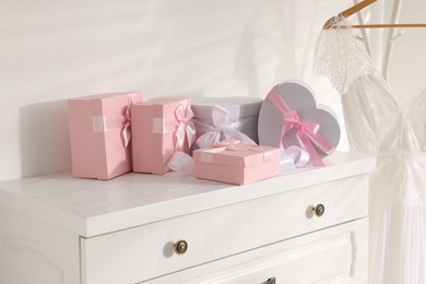 Photo of Gift boxes for wedding day on white chest of drawers indoors