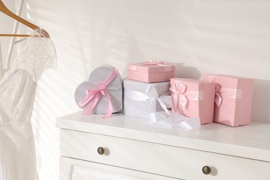 Photo of Gift boxes for wedding day on white chest of drawers indoors