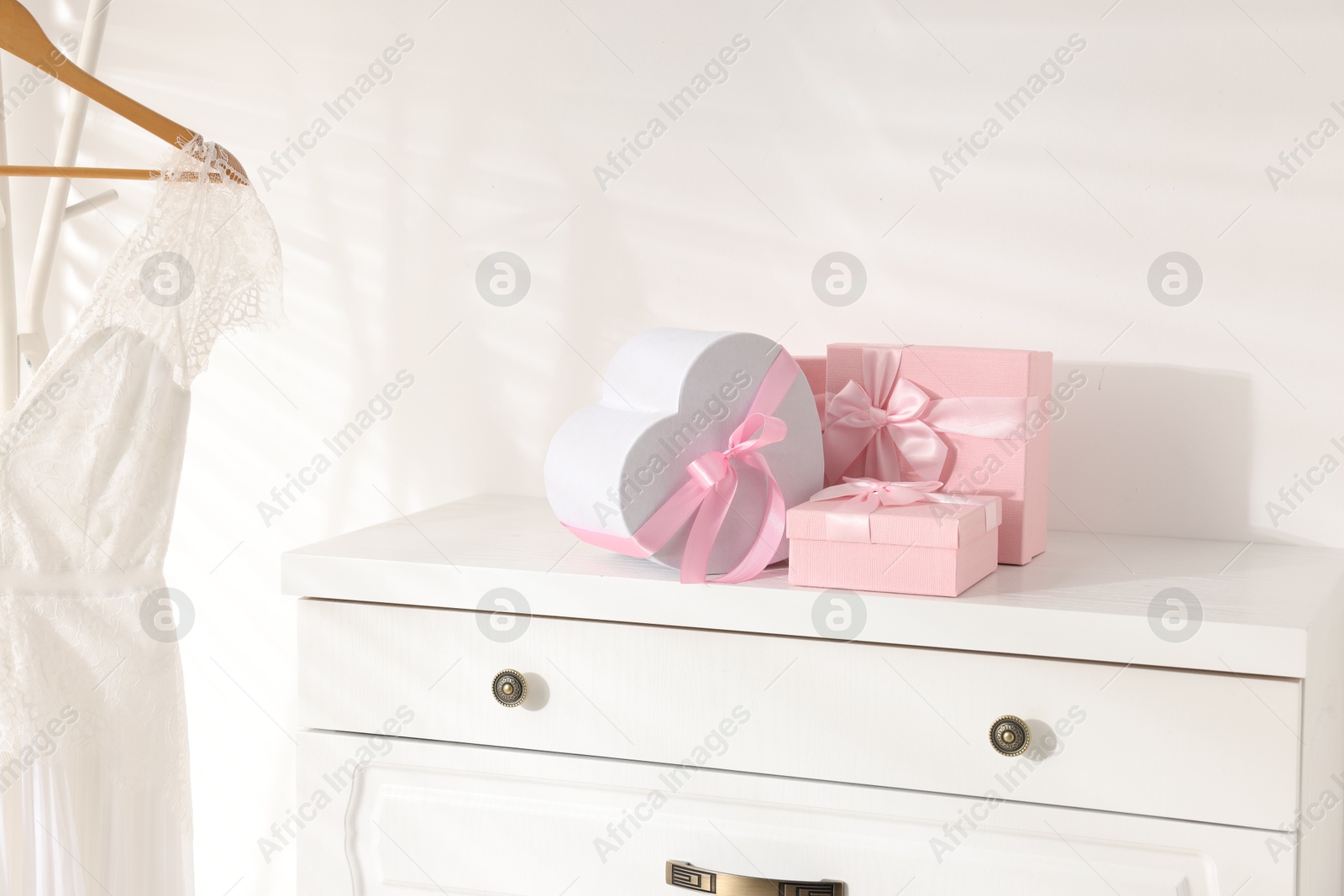 Photo of Gift boxes for wedding day on white chest of drawers indoors