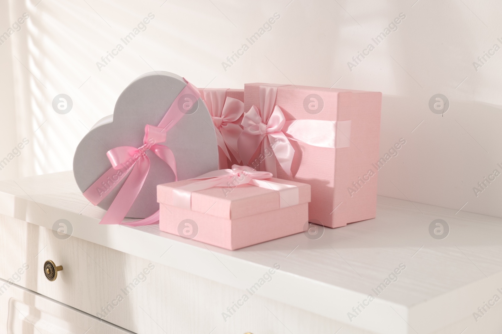 Photo of Gift boxes for wedding day on white chest of drawers indoors