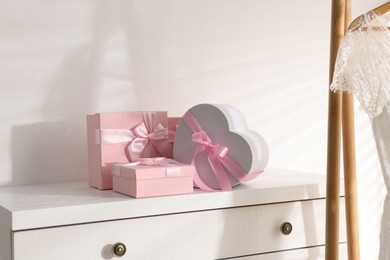 Photo of Gift boxes for wedding day on white chest of drawers indoors