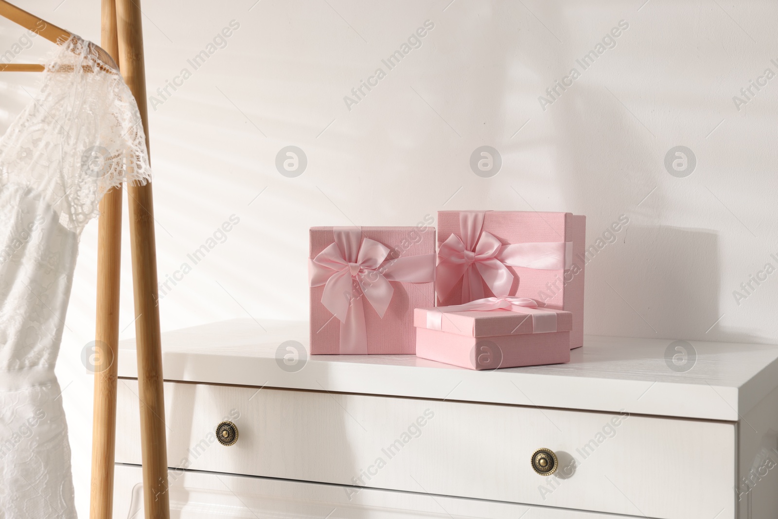 Photo of Gift boxes for wedding day on white chest of drawers indoors