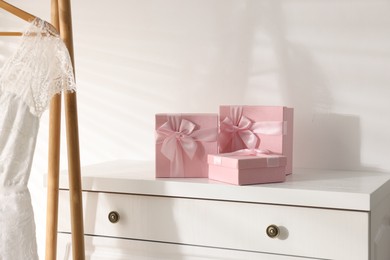 Photo of Gift boxes for wedding day on white chest of drawers indoors