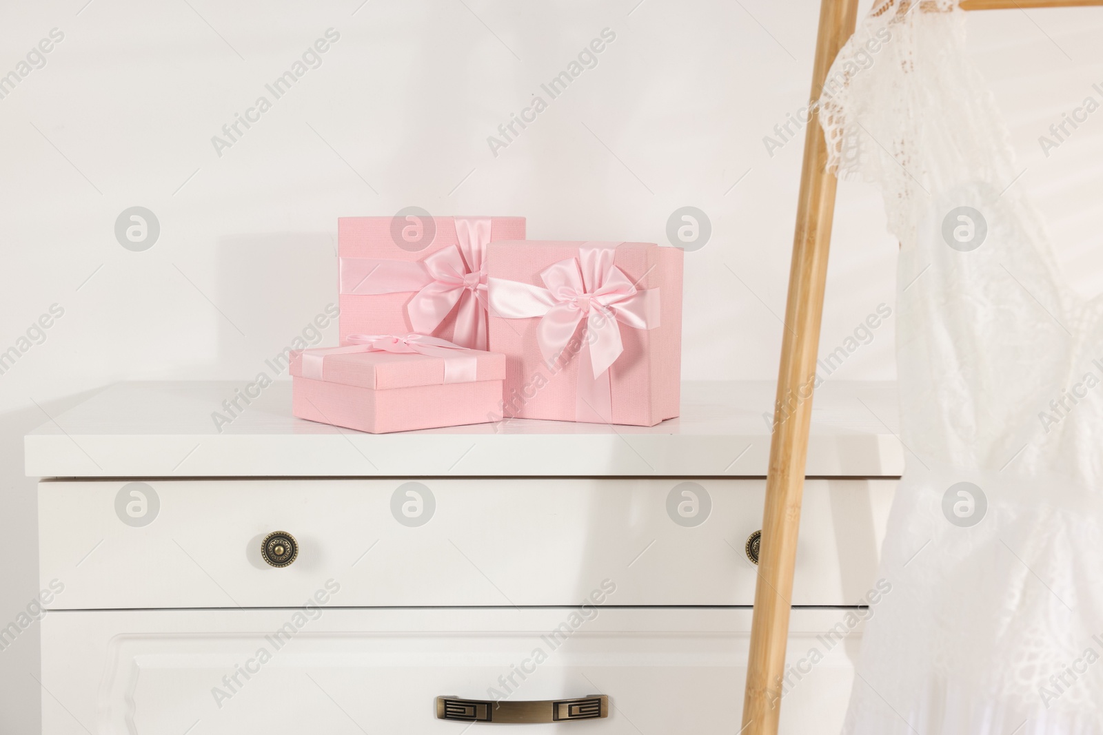 Photo of Gift boxes for wedding day on white chest of drawers indoors