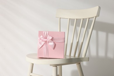 Photo of Gift box for wedding day on chair near white wall