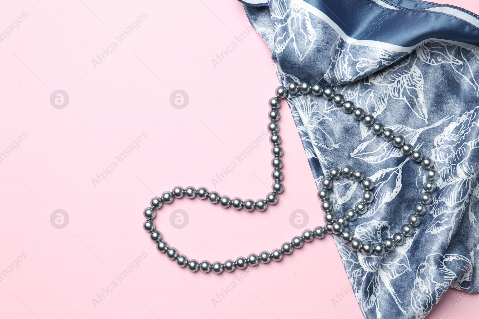 Photo of Beautiful scarf and pearl necklace on light pink background, top view. Stylish accessories