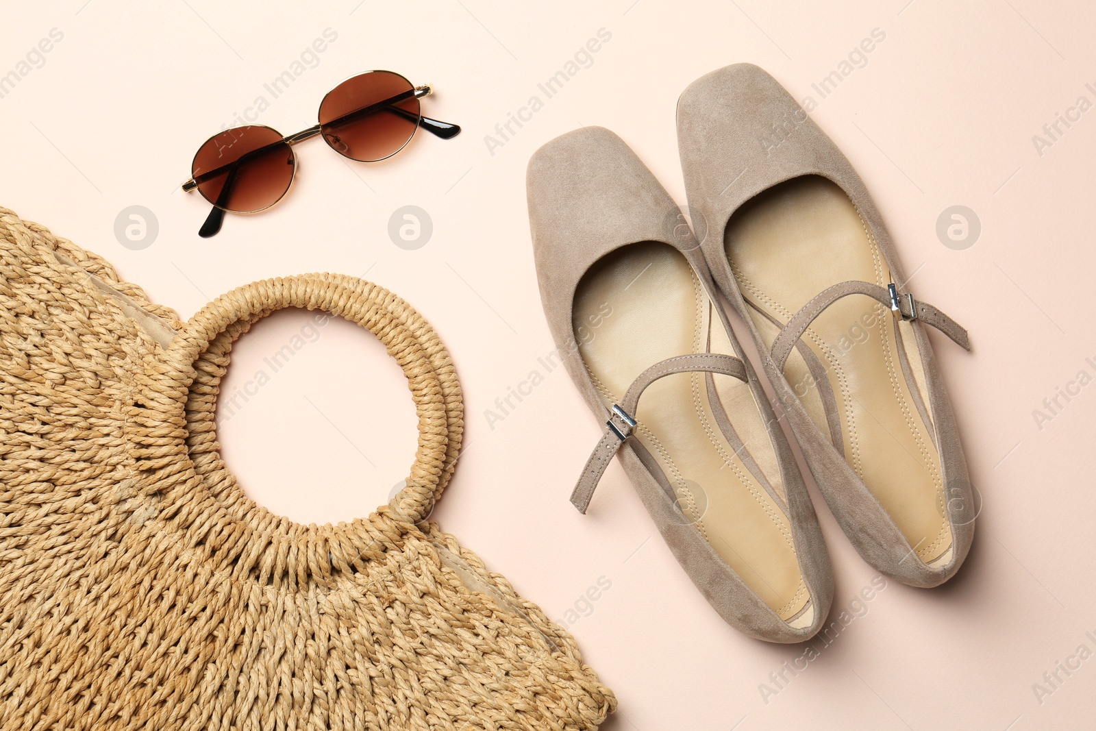 Photo of Wicker bag, shoes and sunglasses on beige background, flat lay. Stylish accessories