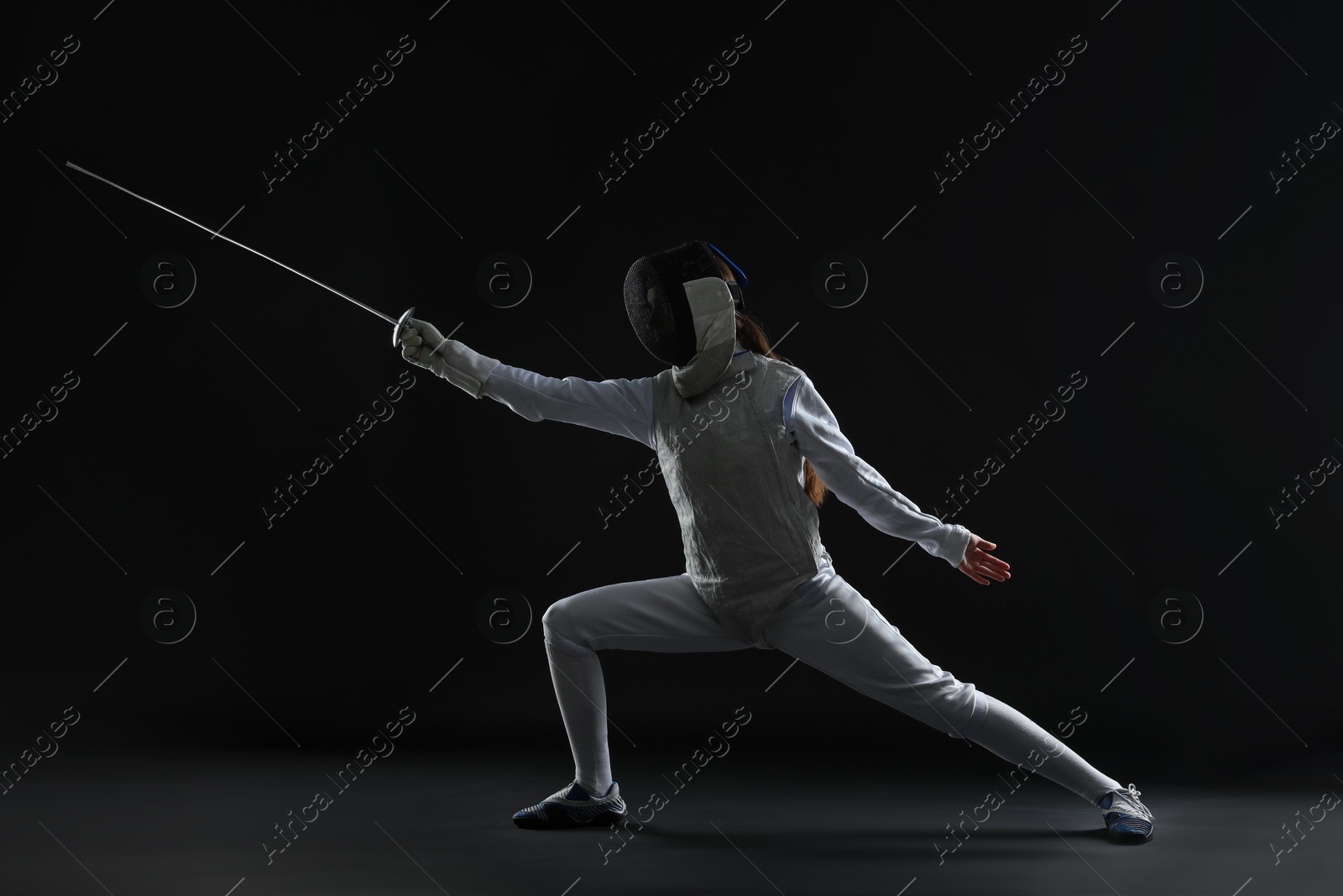 Photo of Fencer with epee practicing on dark background