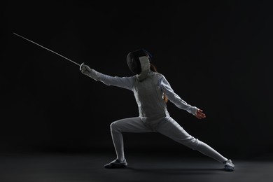 Photo of Fencer with epee practicing on dark background