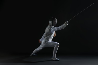 Photo of Fencer with epee practicing on dark background