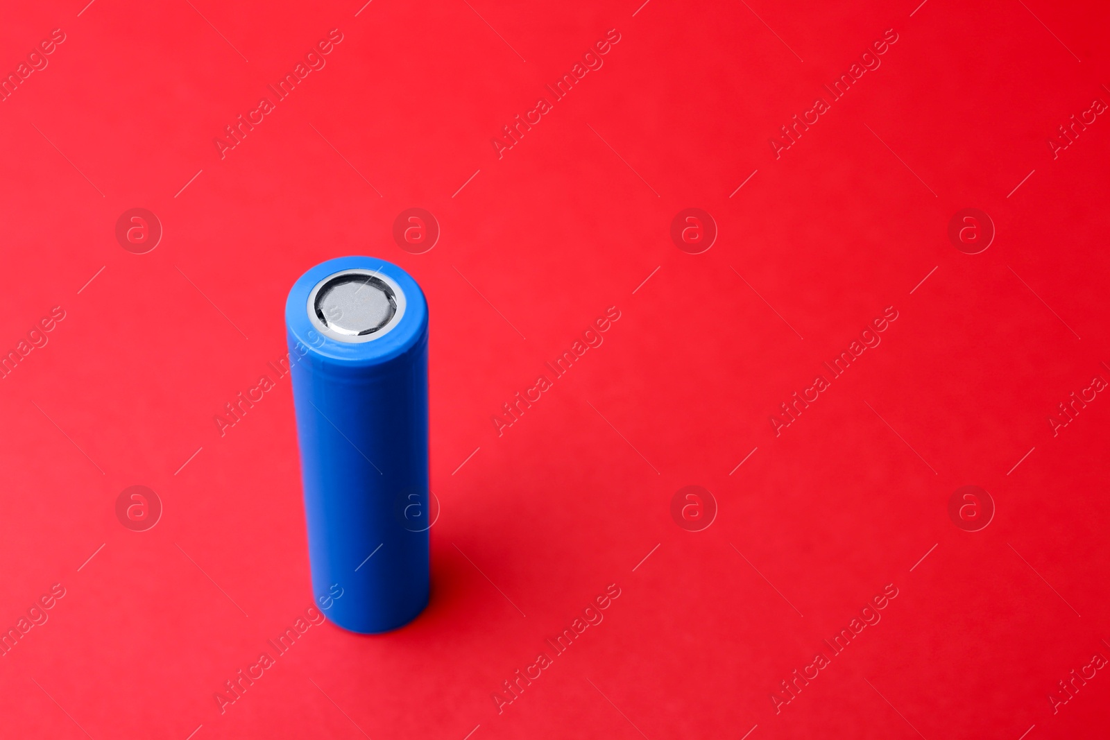 Photo of One AA cell battery on red background, closeup. Space for text