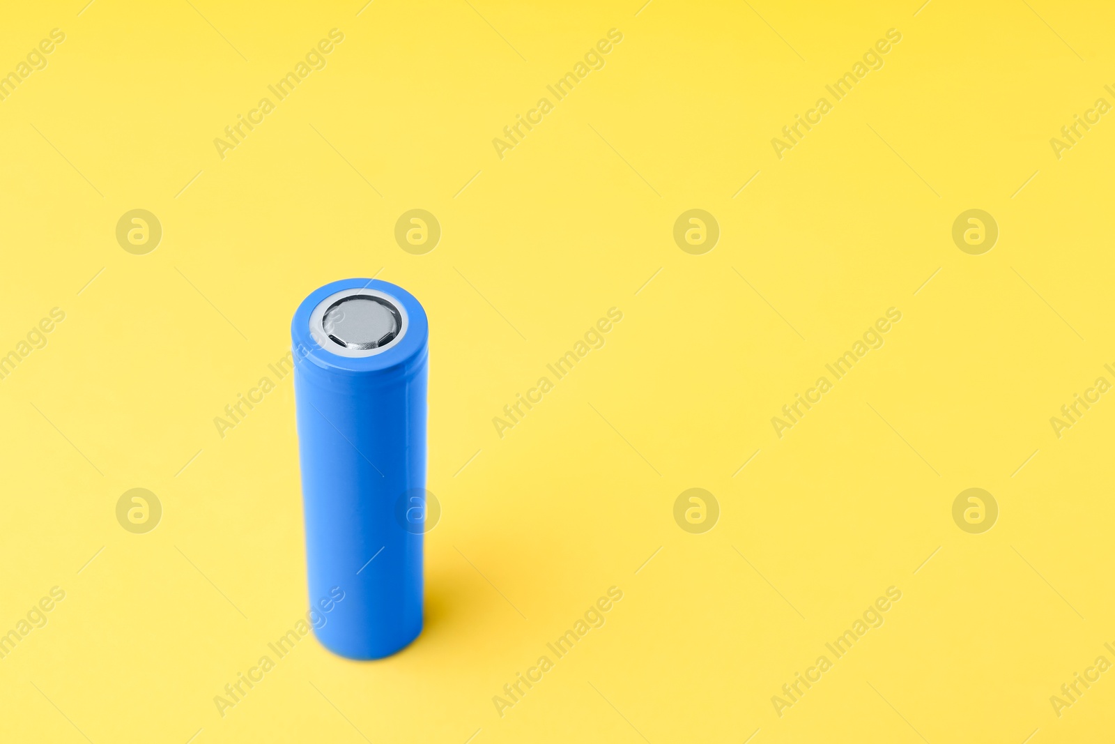 Photo of One AA cell battery on yellow background, closeup. Space for text