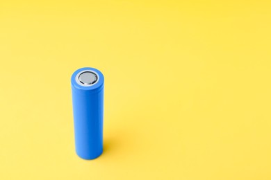 Photo of One AA cell battery on yellow background, closeup. Space for text