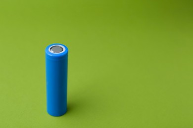 Photo of One AA cell battery on green background, closeup. Space for text