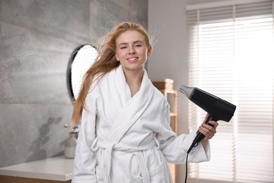 Photo of Beautiful young woman drying her hair in bathroom