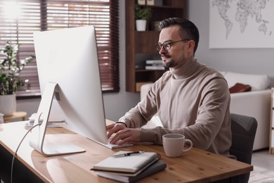 Photo of Handsome man working with computer at desk indoors. Home office