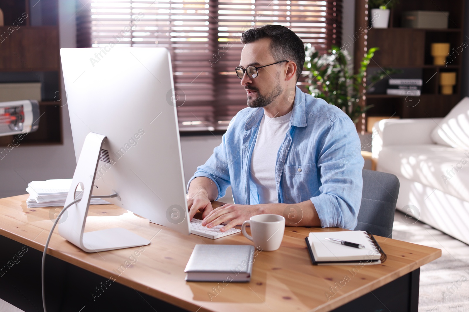 Photo of Handsome man working with computer at desk indoors. Home office