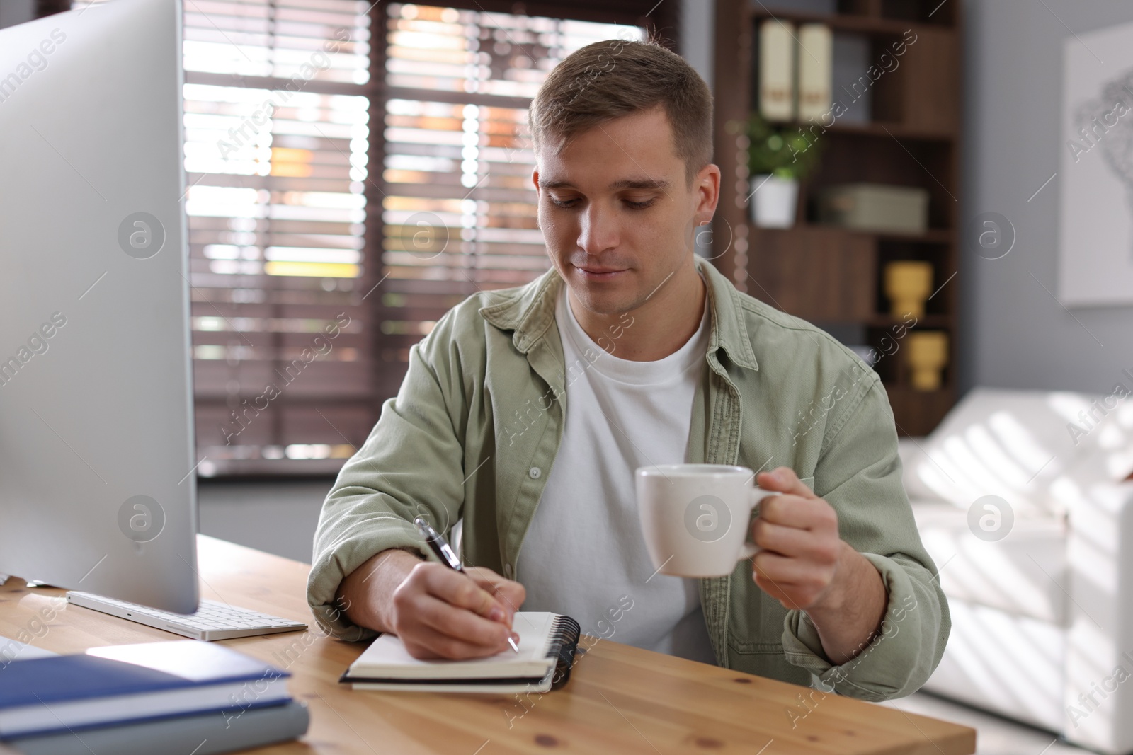 Photo of Handsome man working with computer at desk indoors. Home office