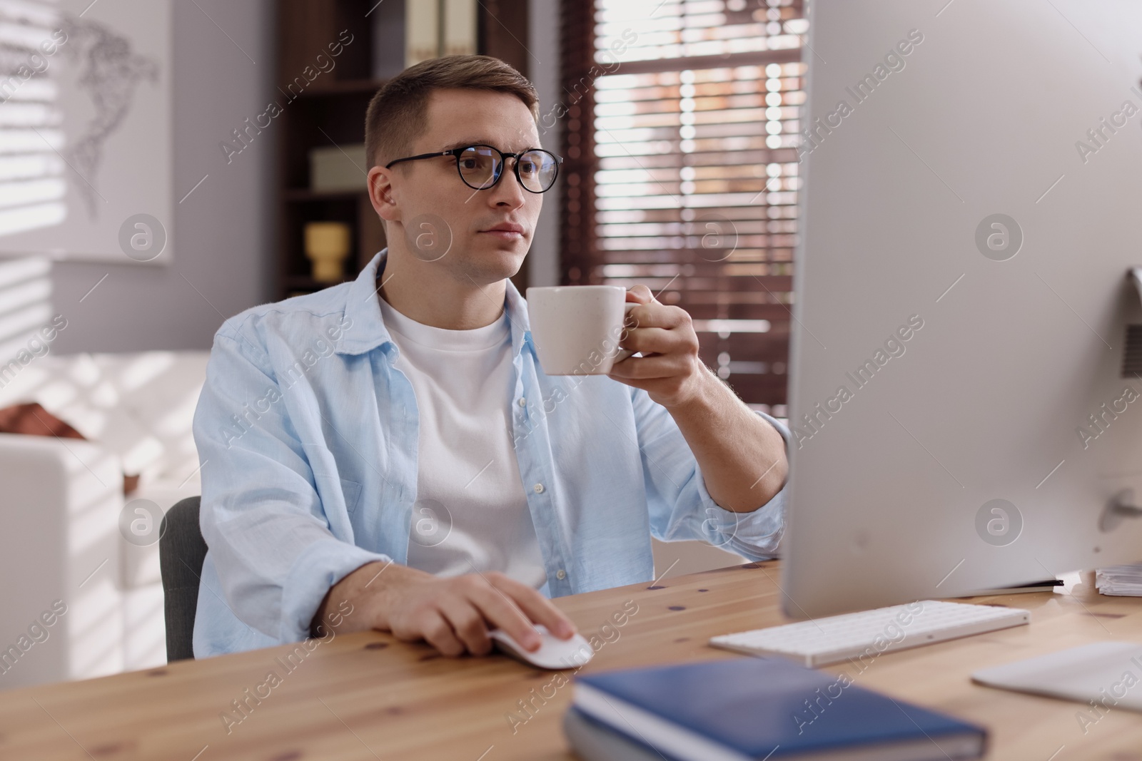 Photo of Handsome man working with computer at desk indoors. Home office