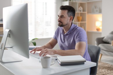 Photo of Handsome man working with computer at desk indoors. Home office