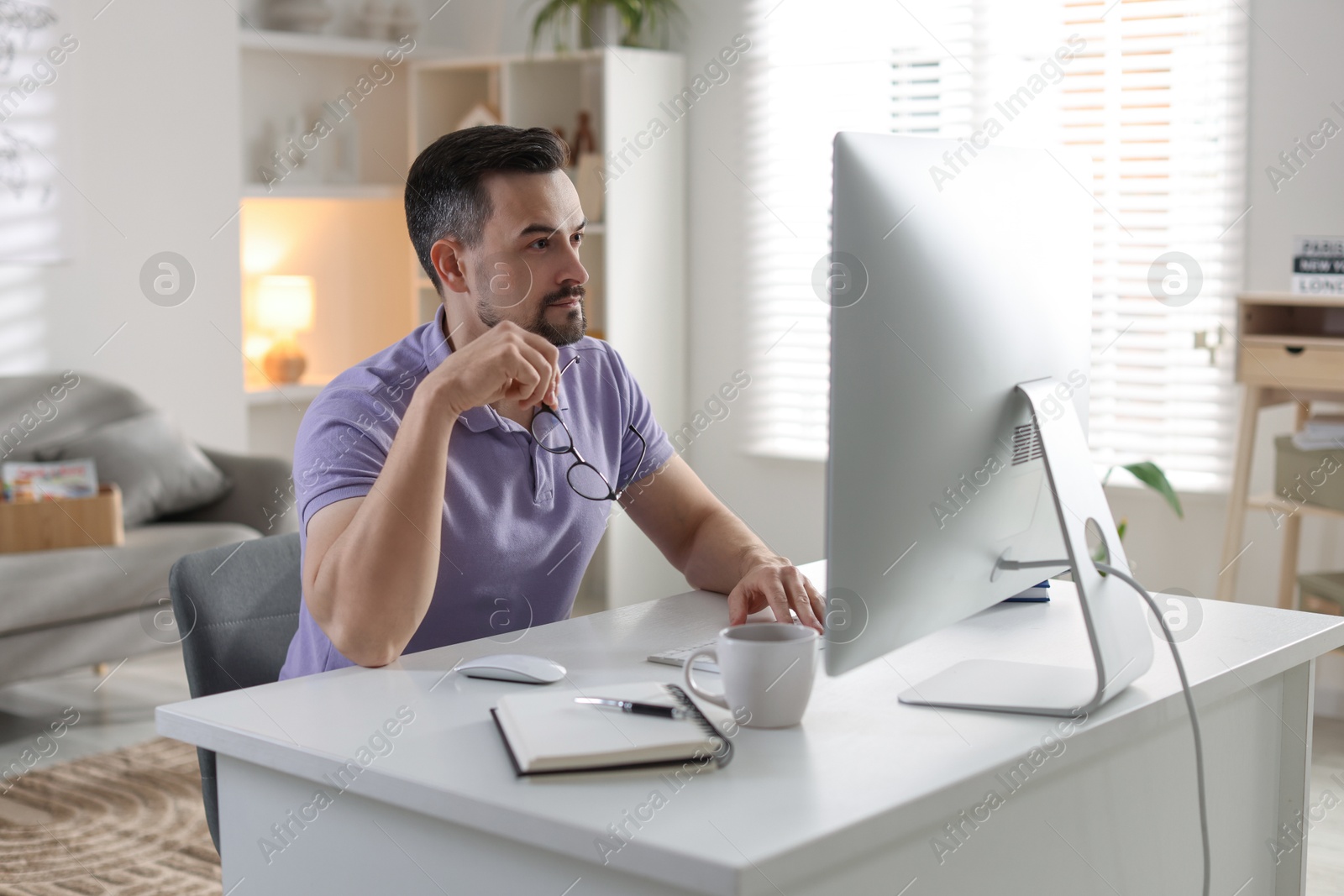 Photo of Handsome man working with computer at desk indoors. Home office