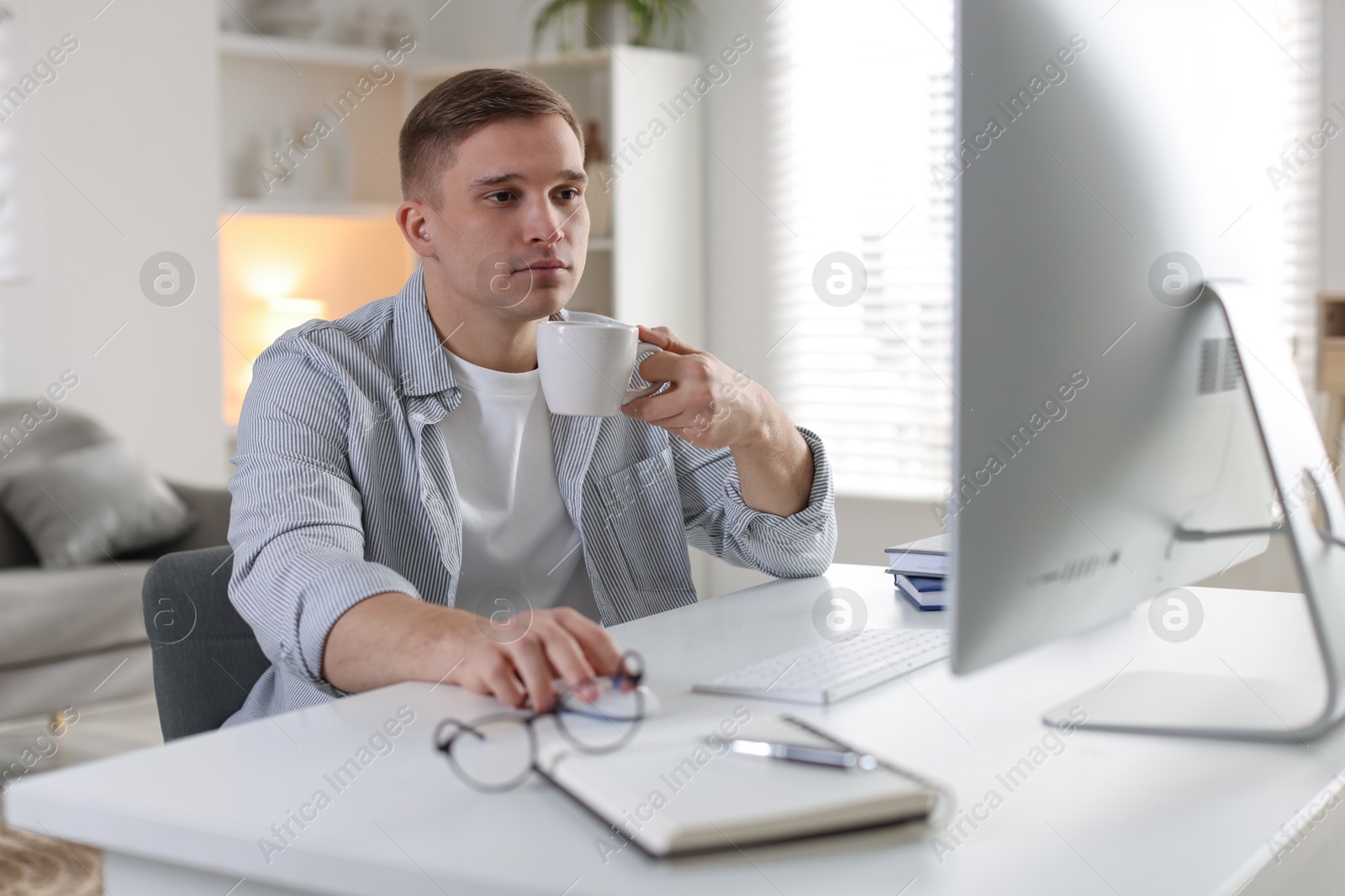 Photo of Handsome man working with computer at desk indoors. Home office