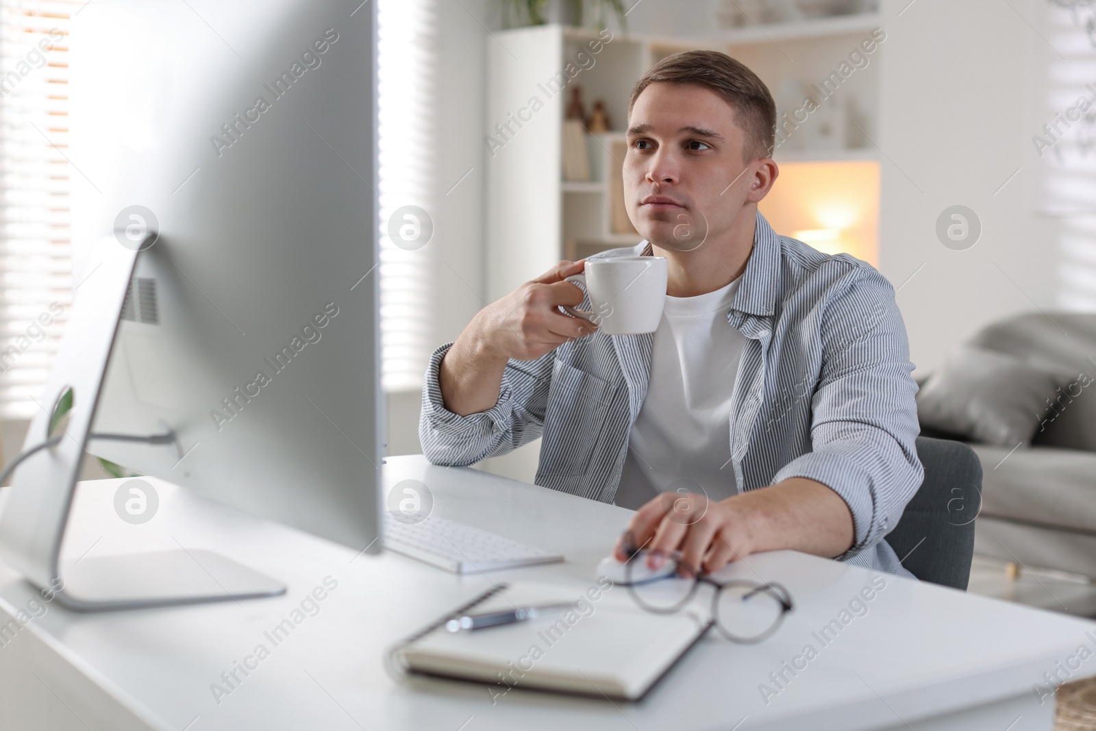 Photo of Handsome man working with computer at desk indoors. Home office