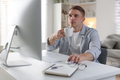 Photo of Handsome man working with computer at desk indoors. Home office