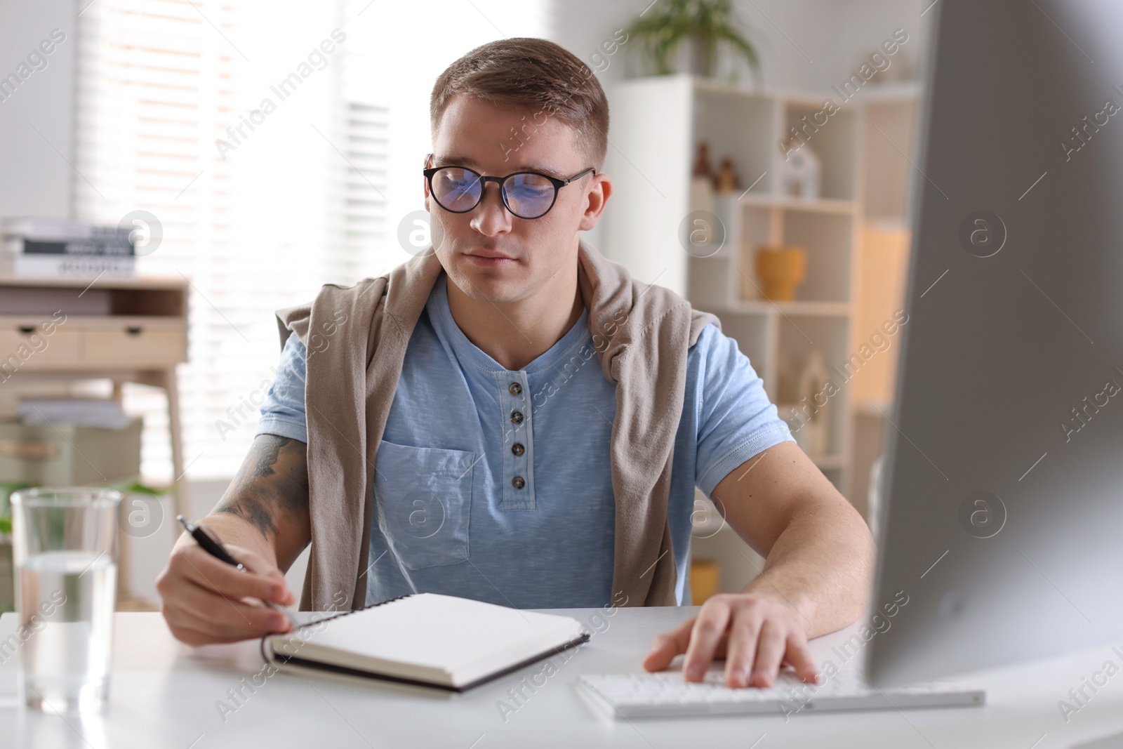 Photo of Handsome man working with computer at desk indoors. Home office