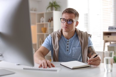 Photo of Handsome man working with computer at desk indoors. Home office