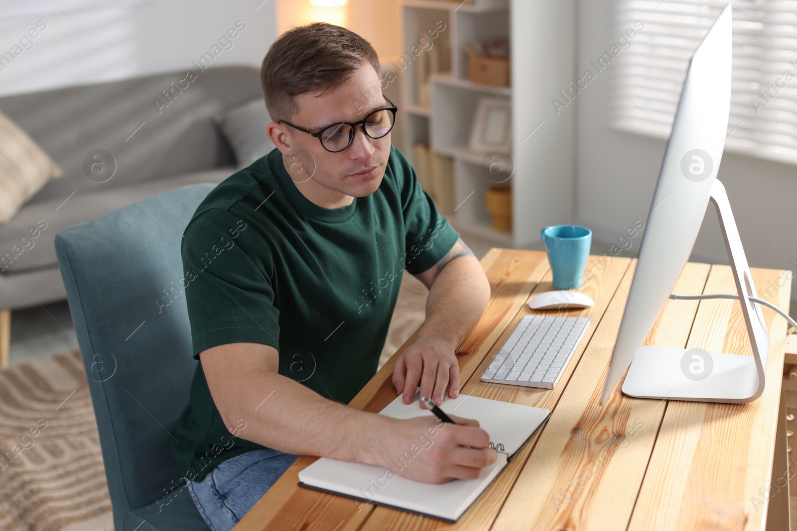 Photo of Handsome man working with computer at desk indoors. Home office