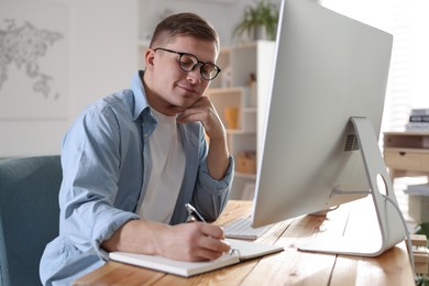 Photo of Handsome man working with computer at desk indoors. Home office