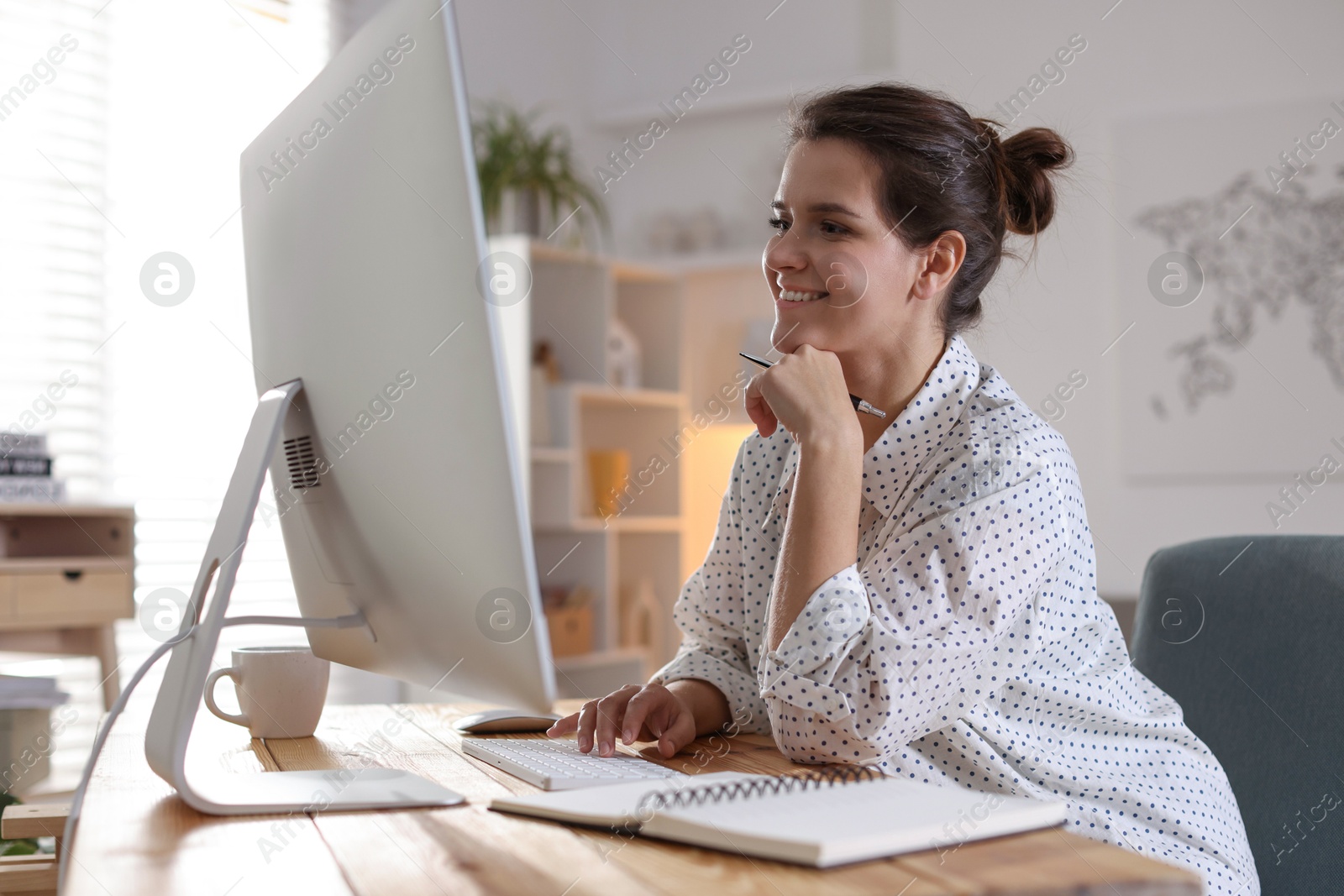 Photo of Happy woman working with computer at desk indoors. Home office