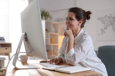 Happy woman working with computer at desk indoors. Home office