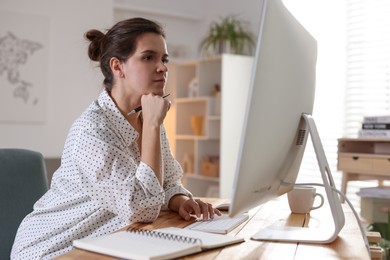 Photo of Beautiful woman working with computer at desk indoors. Home office