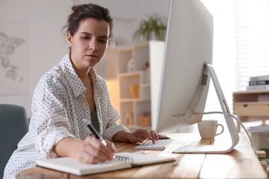 Photo of Beautiful woman working with computer at desk indoors. Home office