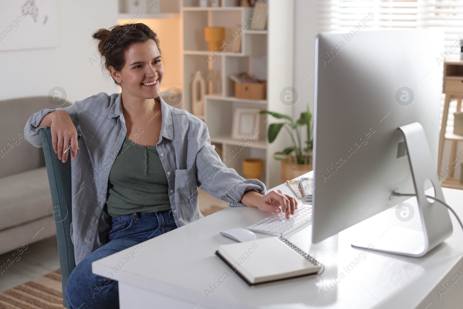 Photo of Happy woman working with computer at desk indoors. Home office