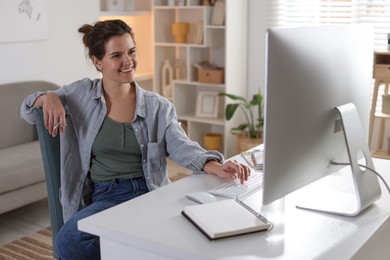 Photo of Happy woman working with computer at desk indoors. Home office