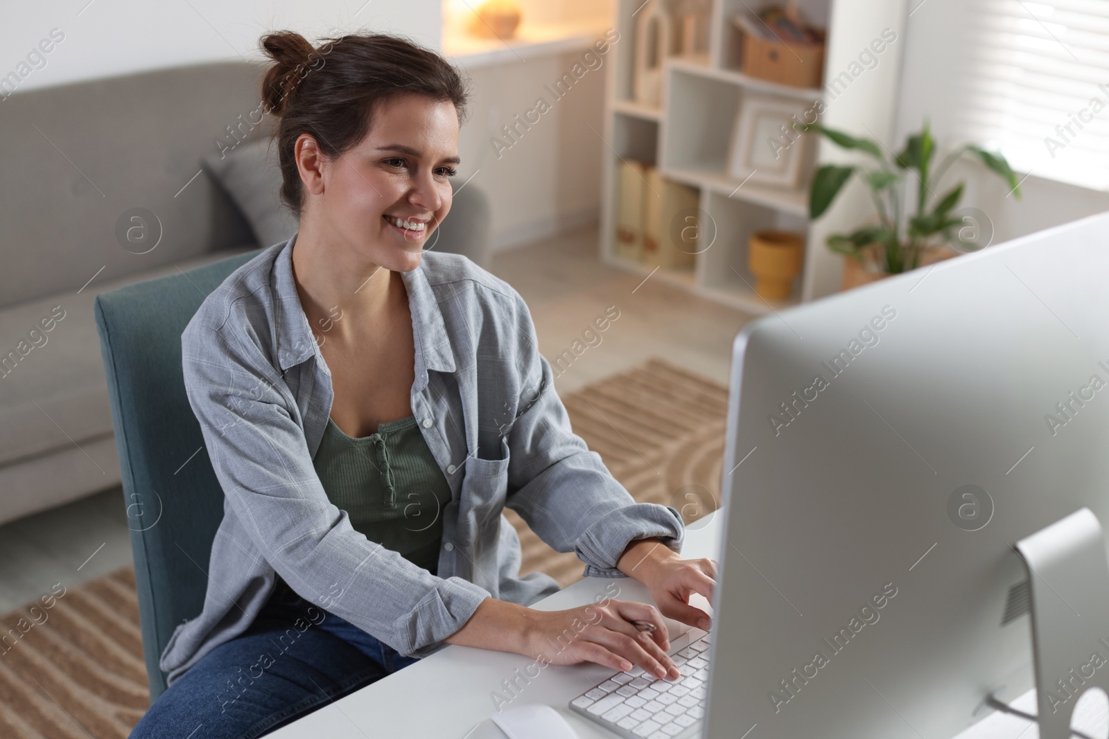 Photo of Happy woman working with computer at desk indoors. Home office