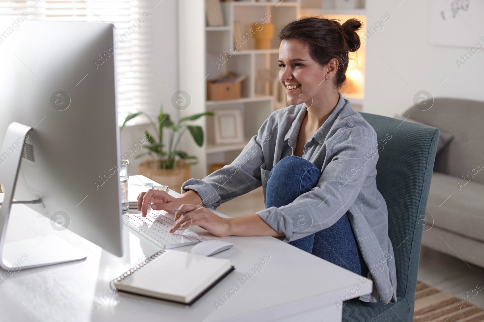 Photo of Happy woman working with computer at desk indoors. Home office