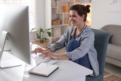 Happy woman working with computer at desk indoors. Home office