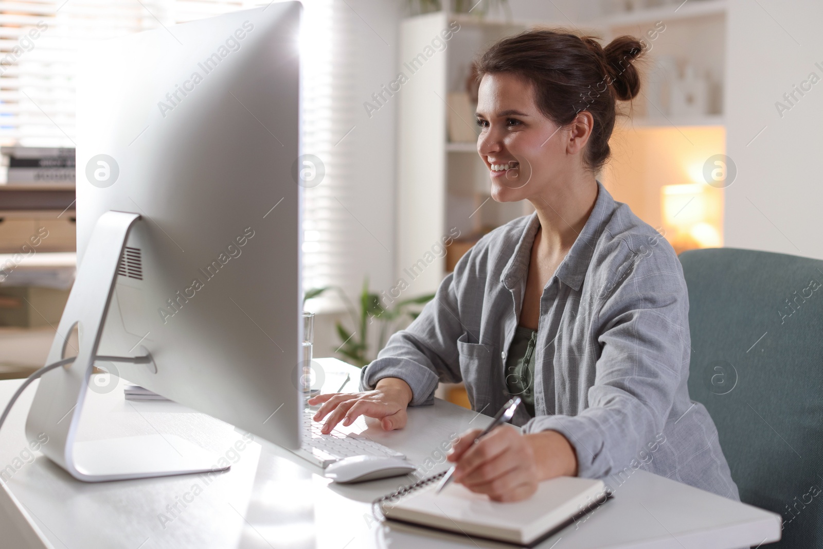 Photo of Happy woman working with computer at desk indoors. Home office