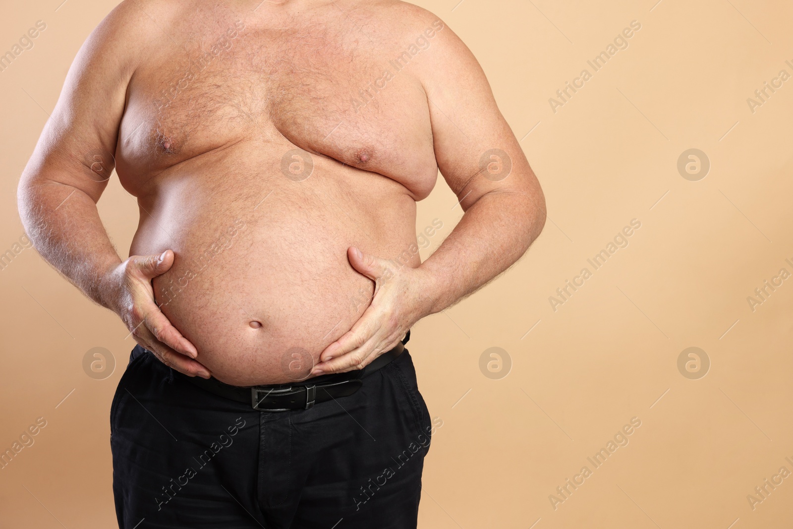 Photo of Overweight problem. Man with excessive belly fat on beige background, closeup. Space for text