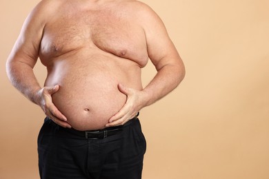 Photo of Overweight problem. Man with excessive belly fat on beige background, closeup. Space for text