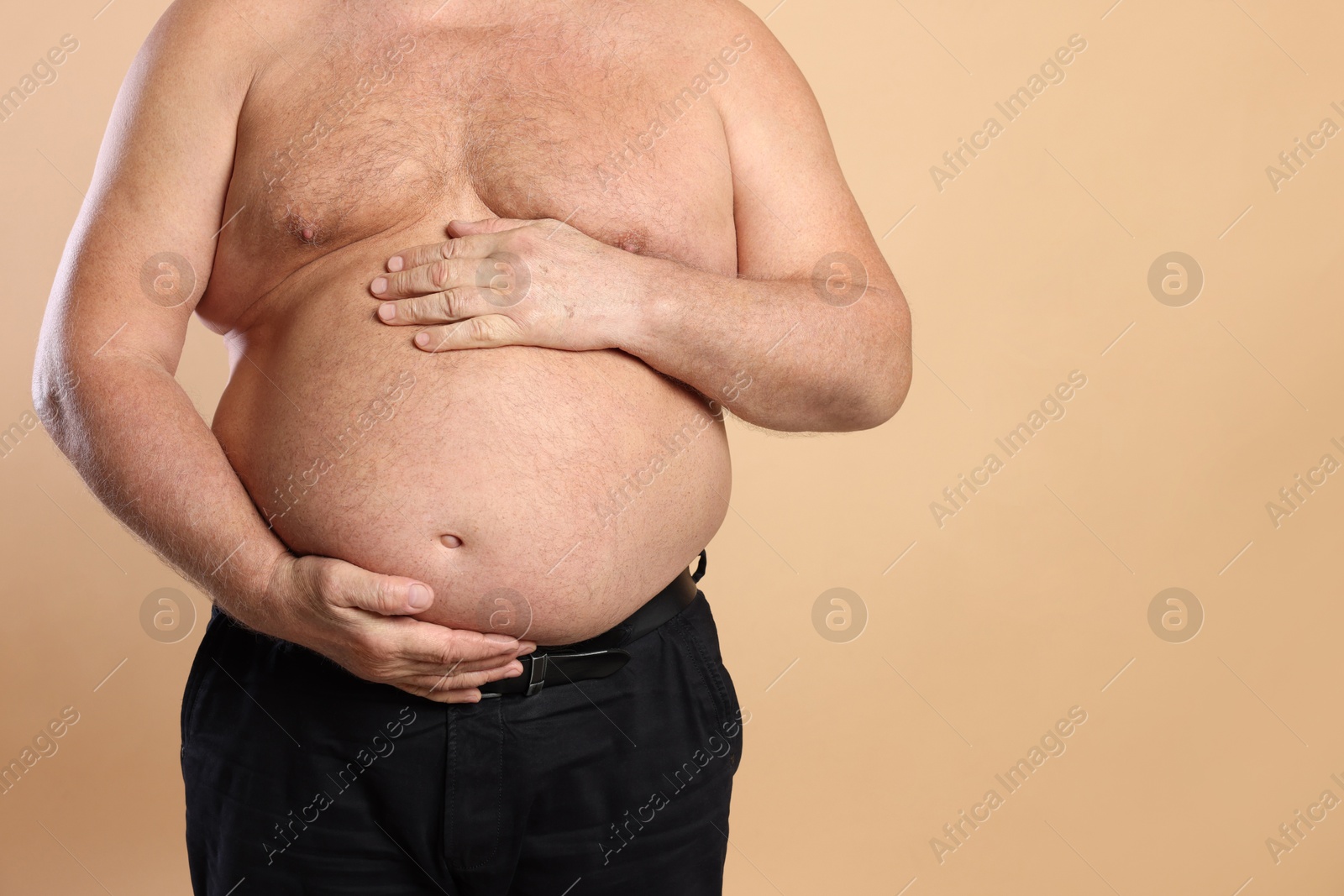 Photo of Overweight problem. Man with excessive belly fat on beige background, closeup. Space for text