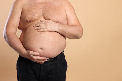 Photo of Overweight problem. Man with excessive belly fat on beige background, closeup. Space for text