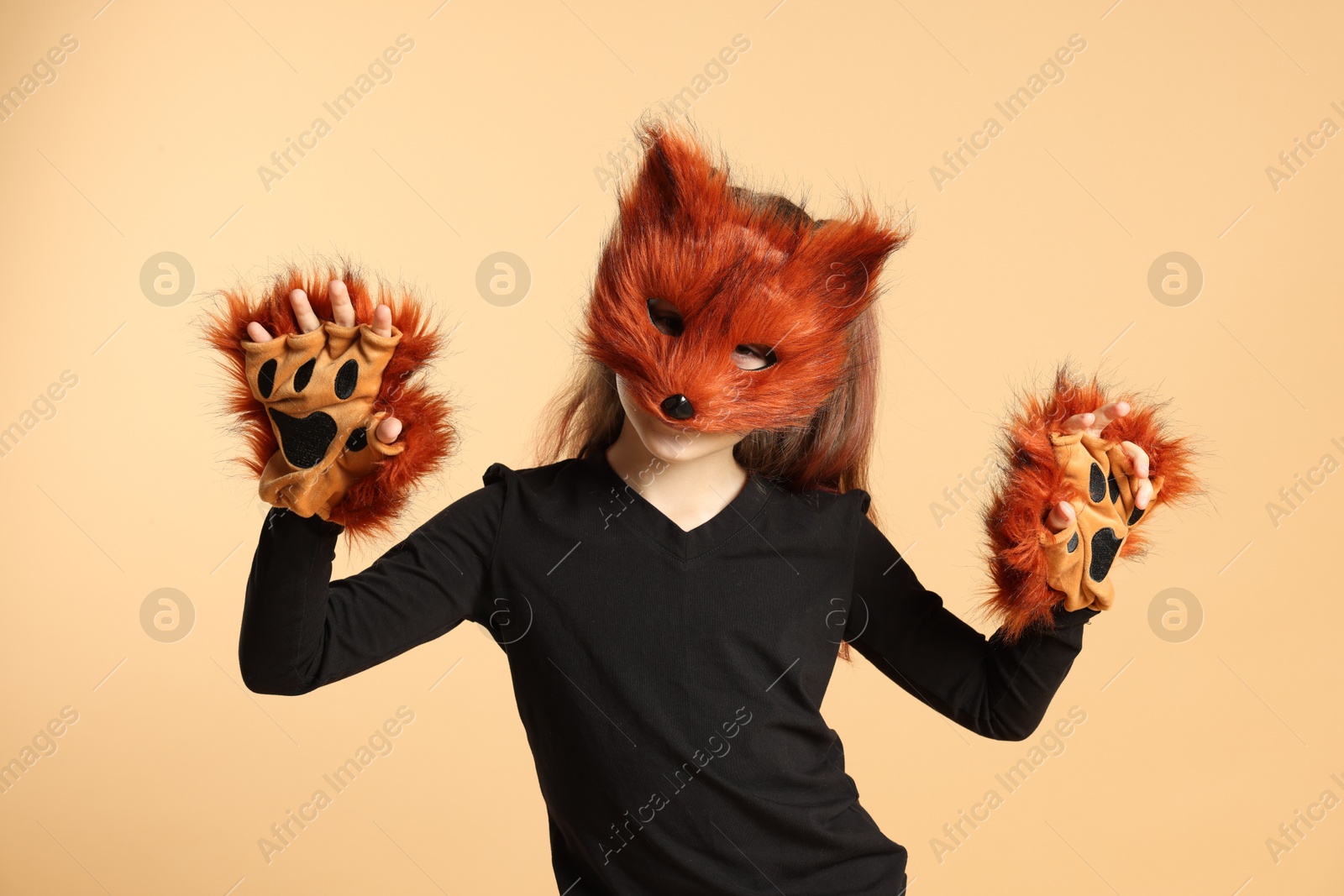 Photo of Quadrobics. Girl wearing fox mask and gloves on beige background