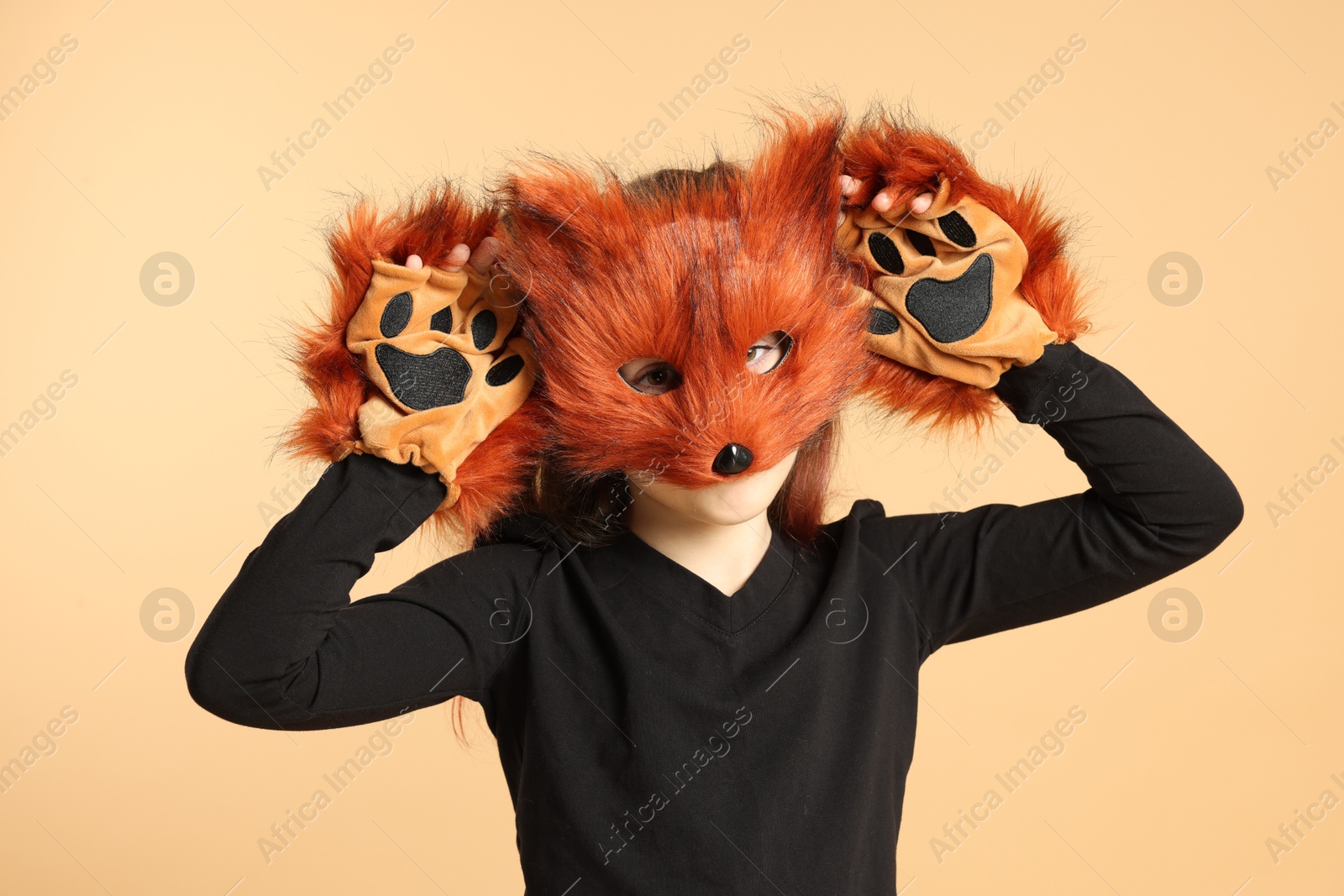 Photo of Quadrobics. Girl wearing fox mask and gloves on beige background